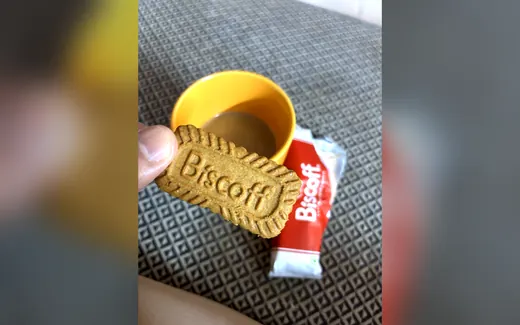 A Lotus Biscoff biscuit beside a cup of chai