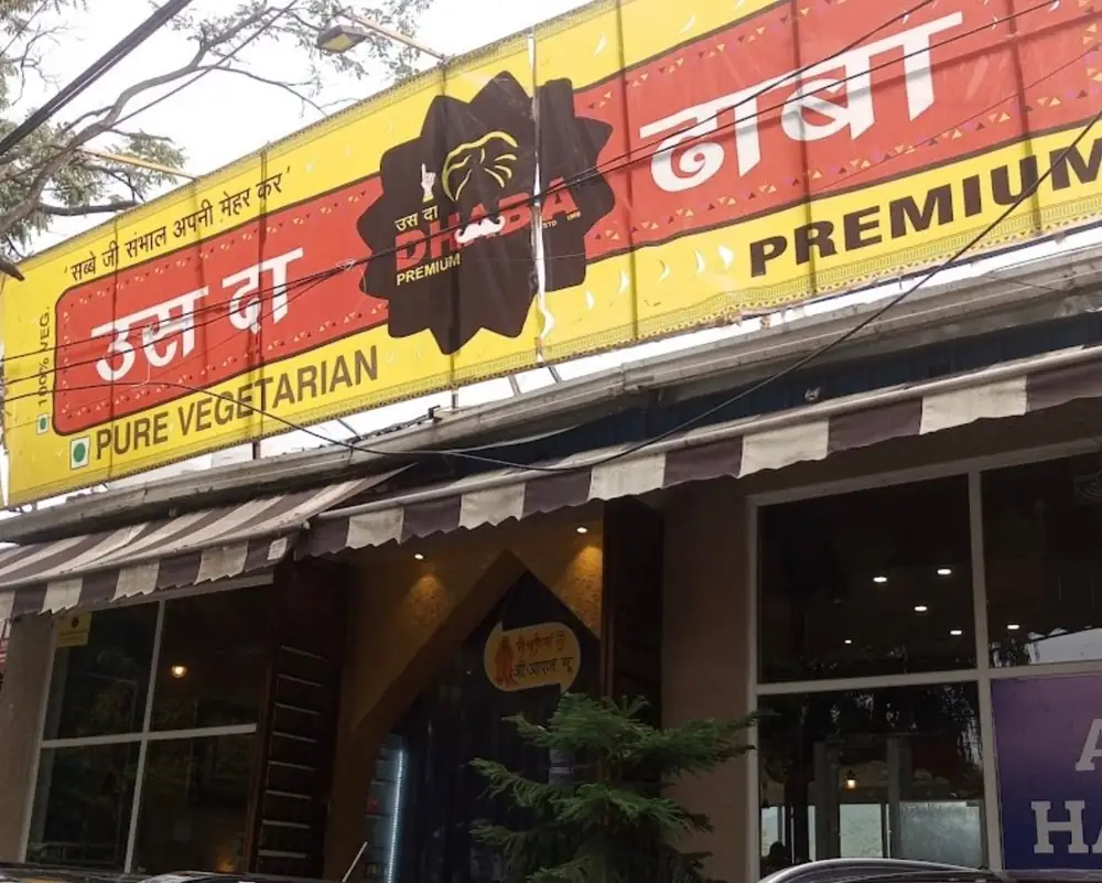 The yellow and red signboard of Uss da Dhaba Premium in Dehradun
