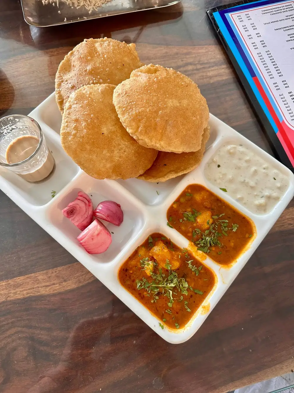 Aloo puri thali with two potato curries, curd, onion and a glass of chai