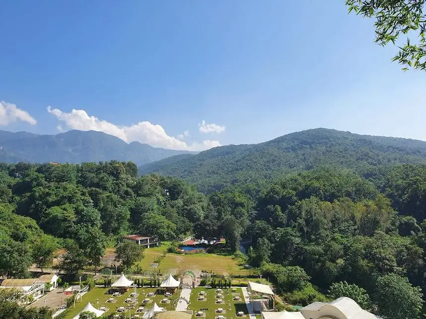Green Doon valley with forested hills and blue sky, seen from the dining hall