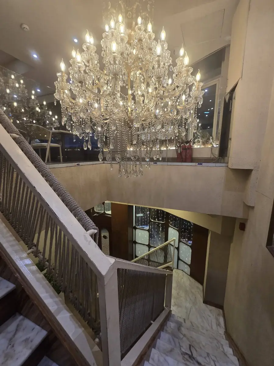 A large crystal chandelier hanging over the marble staircase at Miti
