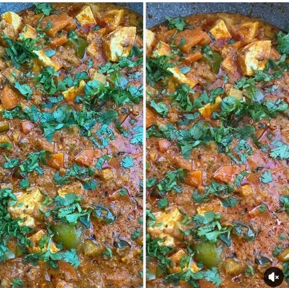 A wide pan of smoky veg angara with paneer, peppers and a heavy scatter of fresh coriander