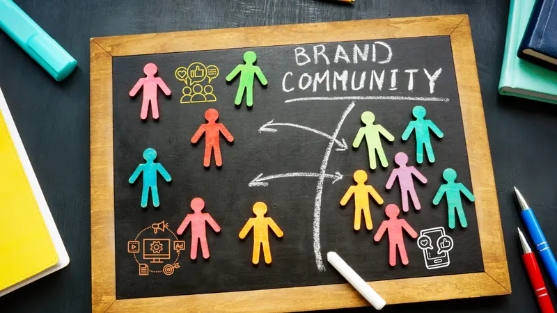 Wooden figures grouped around a chalkboard reading Brand Community, with marketing icons drawn around them